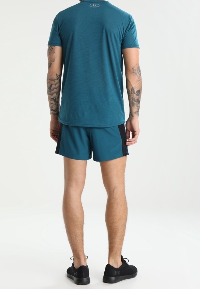 Camiseta atlética color teal y pantalones cortos teal con acentos negros, diseño ajustado, mangas cortas y tela transpirable, usados con zapatos negros.