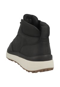 Botines de cuero negro con un acabado texturizado, que presentan un collar acolchado, una entresuela blanca y una suela de goma marrón.