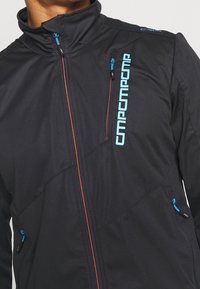 Schwarze Jacke mit hohem Kragen, blauen Akzenten und kontrastierendem orangefarbenem Reißverschluss. Mehrere Reißverschlusstaschen für Stauraum.