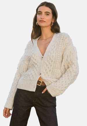 Cremefarbener Strickcardigan mit Fransenärmeln, V-Ausschnitt und Knopfverschluss. Gerippter Saum und aufwändige Texturdetails überall.