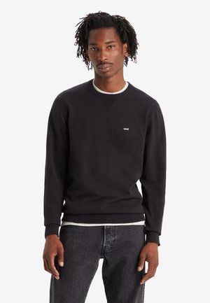 Felpa nera con collo a girocollo realizzata in cotone, con bordo a coste sul collo e sull'orlo, caratterizzata da un piccolo logo bianco di Levi's sul petto. Indossata con jeans scuri.