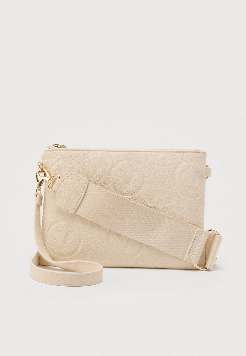 Bolso bandolera de cuero beige con patrones de logotipos circulares en relieve, herrajes dorados y correa ancha ajustable de tela sobre fondo blanco.