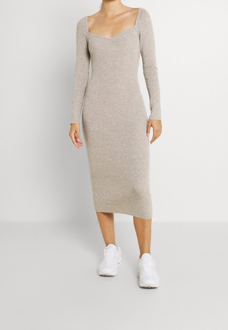 Beige pletené midi šaty s kulatým výstřihem, dlouhými rukávy a přiléhavým střihem, doplněné o bílé sportovní tenisky.
