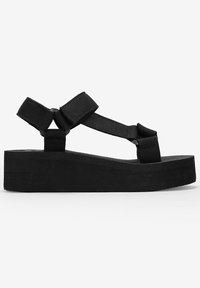 Sandali platform neri con ampie cinghie in tessuto e una suola spessa e testurizzata. Il design include un semplice toe post con doppi dettagli delle cinghie.