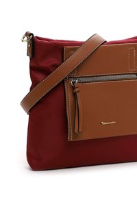 Red nylon shoulder bag with a brown leather front pocket, silver zipper, and adjustable strap, featuring a gold logo detail.