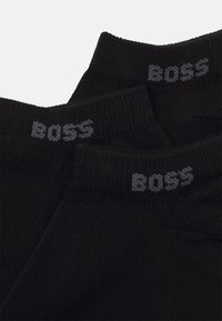 Sorte sokker med ribbet tekstur og et gråt "BOSS" logo ved kanten. Blødt materiale, standard ankel længde og sømløst tådesign.