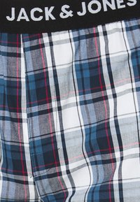 Boxershorts mit einem karierten Muster in Marineblau, Weiß und Rot, mit einem schwarzen elastischen Bund, der "JACK & JONES" in weißem Text zeigt.