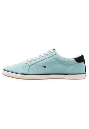 Baskets basses bleu clair avec lacets blancs, petit logo rouge, blanc et bleu sur le côté, patch au talon noir et semelle en caoutchouc blanche.