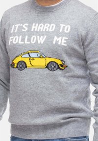 Maglione grigio a maglia con il testo bianco "È DIFFICILE SEGUIRMI" e una grafica pixellata di una macchina sportiva gialla sul davanti.