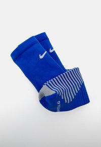 Calzini sportivi blu con parte superiore a costine, logo Nike bianco e motivo a strisce grigie sul tallone. Realizzati in tessuto, progettati per comfort e supporto.