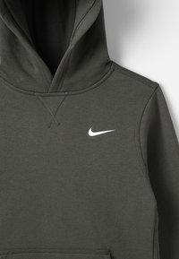 Tummanvihreä puuvillainen huppari, jossa on etutasku ja valkoinen Nike-logo rinnassa. Siinä on teksturoitu huppu ja vahvistetut saumat.