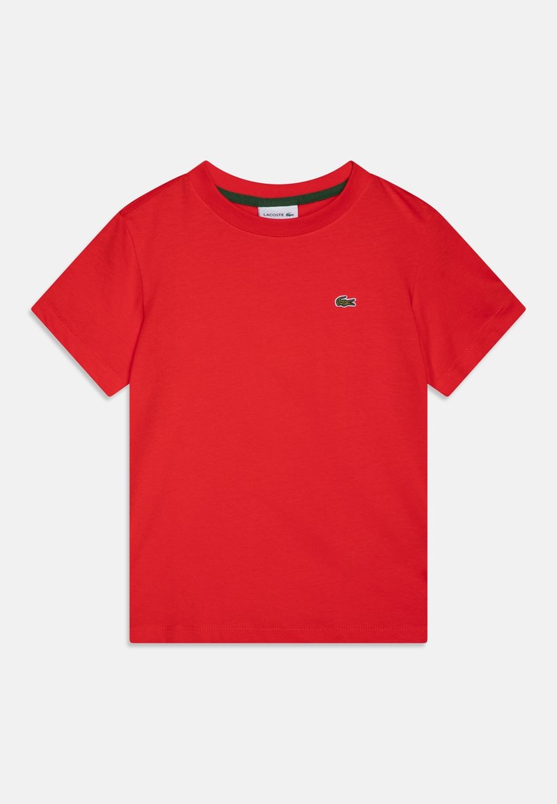 T-shirt en coton rouge avec un col rond. Il arbore un petit logo Lacoste vert sur la poitrine gauche. Manches courtes et ourlet droit.