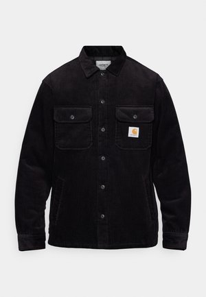 Black corduroy jacket featuring two chest pockets with flaps, a button closure, and a logo patch on the left pocket. Textured fabric.