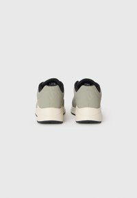 Et par lysegrå sneakers med sort inderside og hvide såler set fra bagsiden på en plain hvid baggrund.