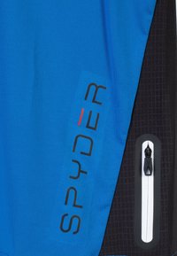 Tela atlética azul con acentos negros, que presenta el logotipo "SPYDER" en negro y rojo. Incluye un bolsillo con cremallera con ribete blanco.