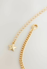 Guld kædearmbånd med en stjernecharms, med en blanding af glatte og strukturerede led og en krabbe-lukning.