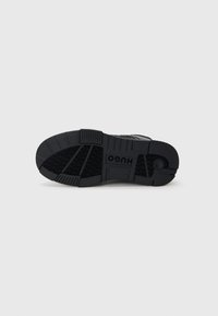 Fekete sneaker talp, texturált barázdákkal, az oldalon dombornyomott logóval. Tartós gumimaterial, tapadásra tervezve.