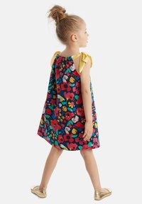 Vestido de estampado floral con fondo azul oscuro, flores multicolores brillantes y tirantes con lazo amarillo. Tela de algodón, corte suelto.