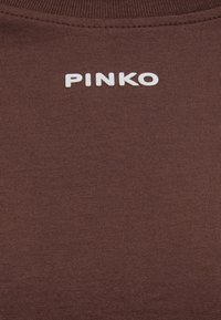 Καφέ πλεκτό ύφασμα με λευκά ανεβασμένα γράμματα που σχηματίζουν τη λέξη «PINKO» κοντά στη λαιμόκοψη.