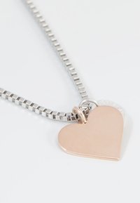 Herzförmige Anhänger-Halskette aus Roségold auf einer silberfarbenen Kette. Mit einer glatten Textur, polierter Oberfläche und minimalen Akzenten.