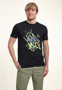 Camiseta de algodón negra con un diseño gráfico colorido que incluye un vehículo y elementos de graffiti en verde y azul. Con mangas cortas y cuello redondo.