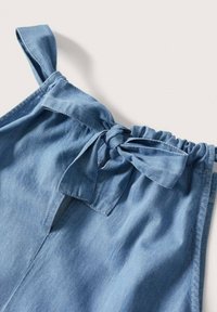 Vêtement en denim de couleur bleu clair, avec des bretelles ajustables nouées, un détail à nouer à la taille et une subtile découpe à l'avant.
