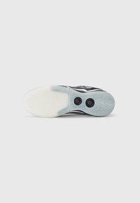 Black athletic shoe sole with a smooth, translucent rubber surface featuring a zigzag pattern and two circular voids for grip enhancement.