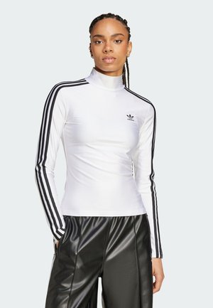 Weißes Langarmoberteil mit Stehkragen, das drei schwarze Streifen an jedem Ärmel und ein Adidas-Logo auf der Brust hat. Kombiniert mit schwarzen Hosen.