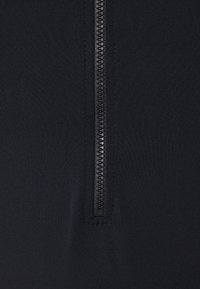 Black zip-up garment with a smooth, textured fabric. Features a central zipper running vertically. No additional patterns or embellishments.