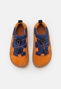 Chaussures en suède orange et en tissu bleu avec une finition texturée, dotées d'un système de laçage à tirette et de semelles en caoutchouc marron.
