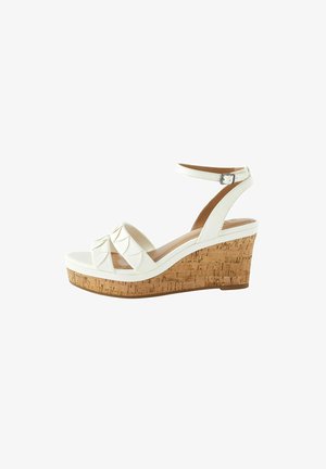 Sandale blanche à talon en liège, avec un design à bandes croisées, une sangle à la cheville ajustable, et une tige en simili cuir lisse.