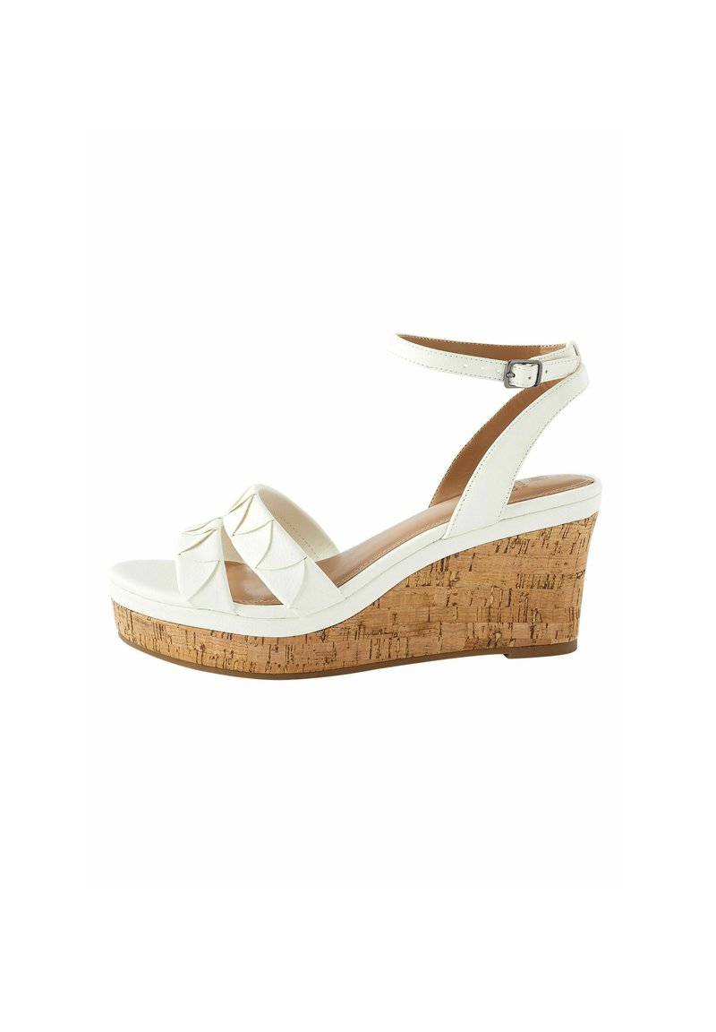 Sandale blanche à talon en liège, avec un design à bandes croisées, une sangle à la cheville ajustable, et une tige en simili cuir lisse.