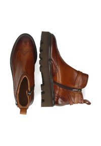 Botas de tobillo de cuero marrón con detalles de brogue, cremallera frontal y suela de goma gruesa. Cuentan con una lengüeta en la parte posterior para facilitar su calzado.