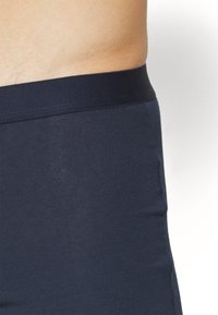 Mørkeblå shorts med elastisk midjebånd laget av et mykt, glatt stoff, med en tett passform og sømløs konstruksjon for komfort.