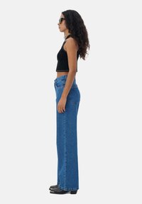 Hoge taille blauwe denim jeans met een rechte snit, voorzien van een vijf-pocket ontwerp en subtiele stiksels, gecombineerd met een zwart crop top.