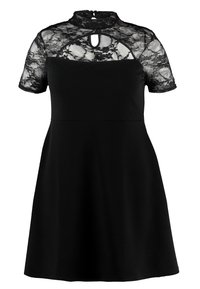 Robe noire avec un haut en dentelle à manches courtes, col haut et détail en trou de clé. La jupe s'évasent à partir de la taille. Texture de tissu douce.