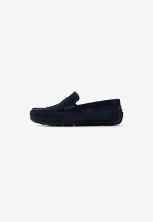 Donkerblauwe suède instap moccasin schoen met gestikte accenten, platte rubberen zool en een ronde neus. Minimalistisch ontwerp zonder extra versieringen.
