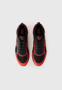 Black and red athletic sneakers with mesh upper, textured overlays, laces, and EA7 branding on the tongue and side.