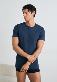 Navy blue cotton t-shirt with a crew neck and short sleeves, featuring a slim fit. Soft texture with minimal branding on the hem.