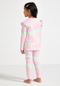 Roze pyjama set met lange mouwen, gekenmerkt door pastelgradiënt strepen, ruche schouderaccenten en aansluitende broekspijpen tot de enkel. Zacht katoenmateriaal.