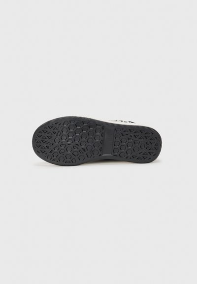 Semelle de chaussure en caoutchouc noir présentant un motif hexagonal, avec une bordure texturée et une section centrale lisse.