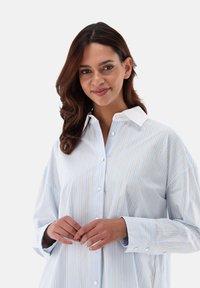 Light blue button-up shirt with white and gold vertical stripes, soft cotton fabric, and a white collar. Features long sleeves and a relaxed fit.