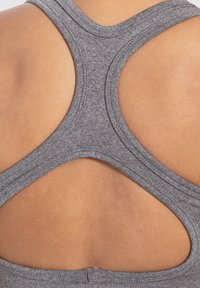 Harmaa urheilullinen tank-top, jossa on urheilullinen selkäosa ja teksturoitu kangas. Sisältää leikkauksia selkäpuolella ilmanvaihtoa varten.