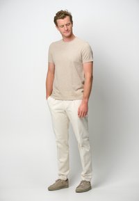 Ljusbeige kortärmad skjorta kombinerad med off-white byxor. Utseendet fulländas med ljusgrå sneakers, som ger en avslappnad outfit.