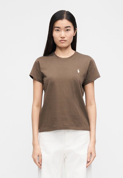 Barna pamut póló kerek nyakkivágással, rövid ujjakkal és egy kis fehér hímzett logóval a bal mellrészen. Nincsenek látható minták.