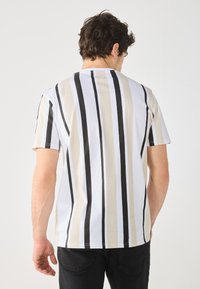 Short-sleeve t-shirt featuring vertical black, beige, and white stripes, made of soft cotton, with a crew neck and a relaxed fit.