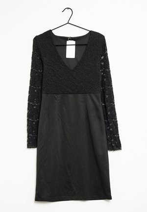 Black knee-length dress with lace long sleeves and bodice, V-neck, hanging on a black hanger with a white tag.