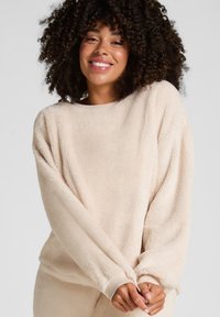 Beige, pluche sweatshirt met lange mouwen, ronde halslijn en aangesloten manchetten, met een zachte textuur en een relaxte pasvorm.
