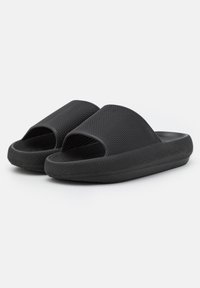 Black slide sandals made of textured rubber with open toe design. Features wide upper straps and a cushioned sole for comfort.