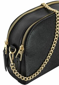 Czarna skórzana torba o fakturze z podwójnymi złotymi suwakami, złotą łańcuszkową rączką oraz metalowymi akcentami. Kompaktowy, zaokrąglony kształt o eleganckim wykończeniu.